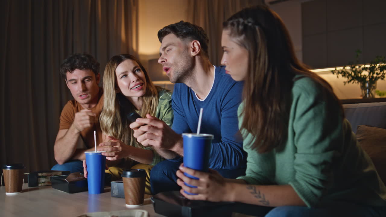 Chilling people watching show turning on television at night apartment close up.