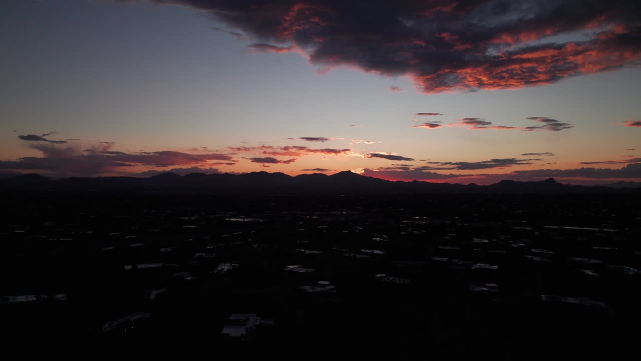 Silhouette of mountains at sunset, peaceful drone shot.