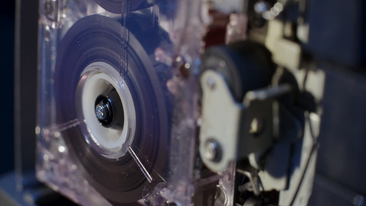 핀치 롤러가 전경에 노출된 마이크로카세트 레코더 릴 회전