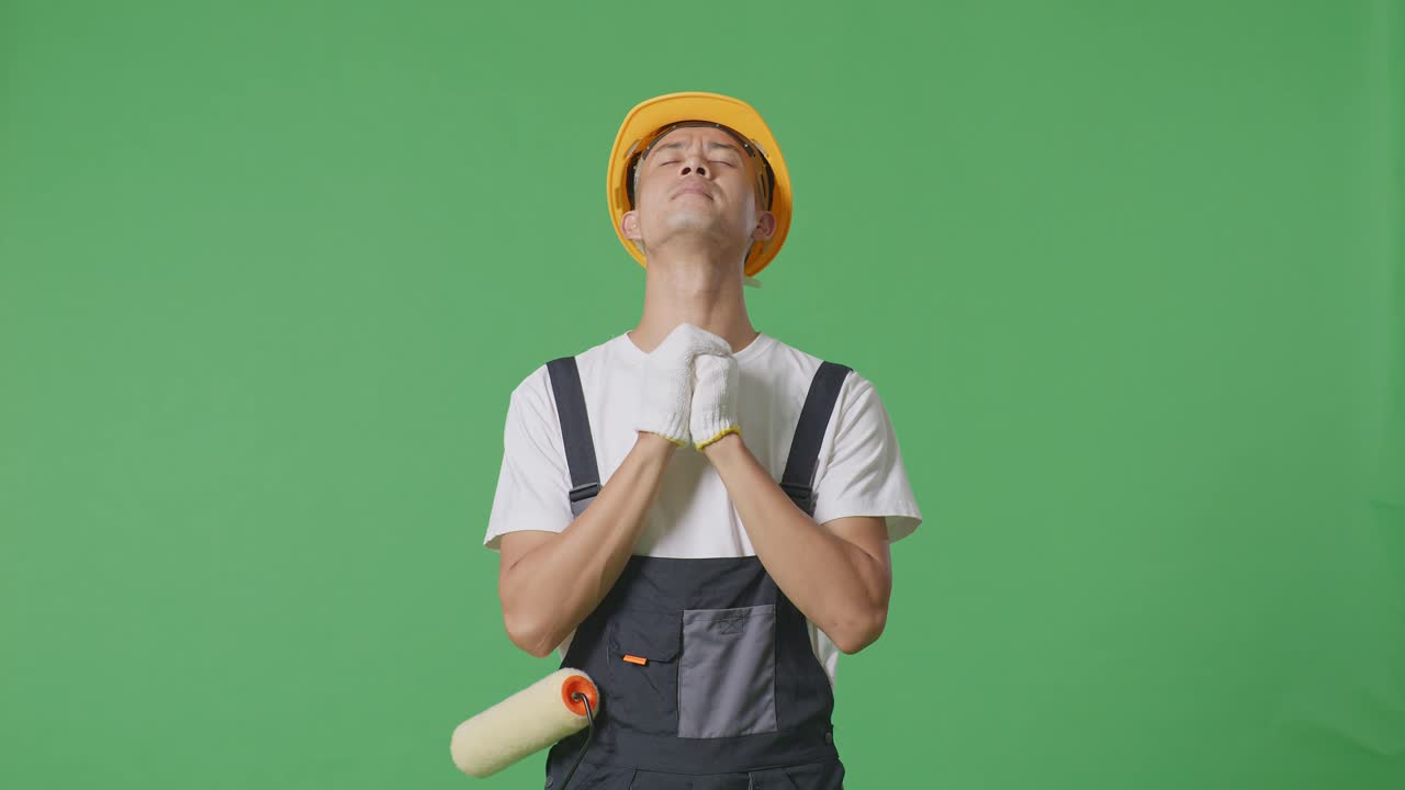Asian Man Painter Wearing Safety Helmet Praying For Something While Standing In The Green Screen Background Studio