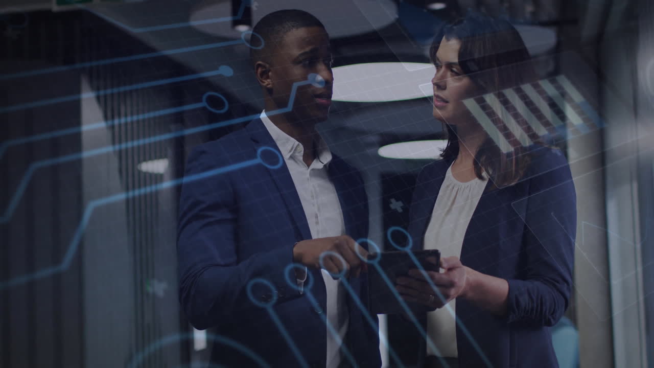 Two professionals reviewing tablet in modern tech office, showing digital circuit graphics overlay