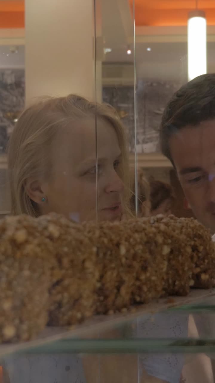Couple heureux regardant de délicieux gâteaux dans une vitrine de pâtisserie