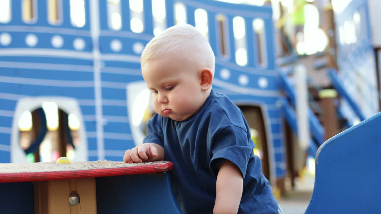 Baby boy playing with sand outdoors. Child development. Children's games on the playground