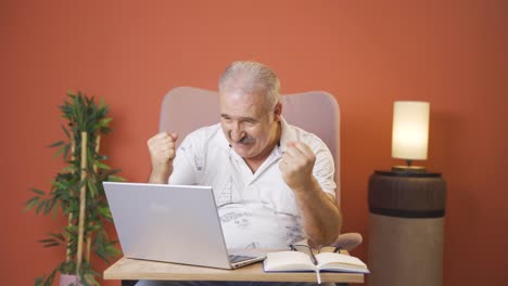 el anciano mira la computadora portátil y se alegra.