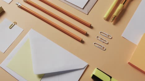 close up of pens, pencils and stationery arranged on beige background, in slow motion