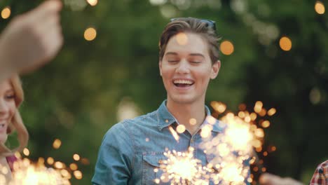 happy friends with sparklers having fun outdoors