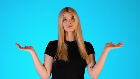clueless young blonde woman, uncertain and unsure gesture, studio portrait