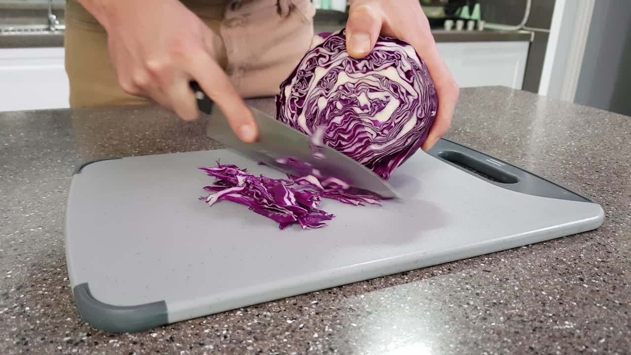 Closeup of a man slicing red cabbage in a kitchen home