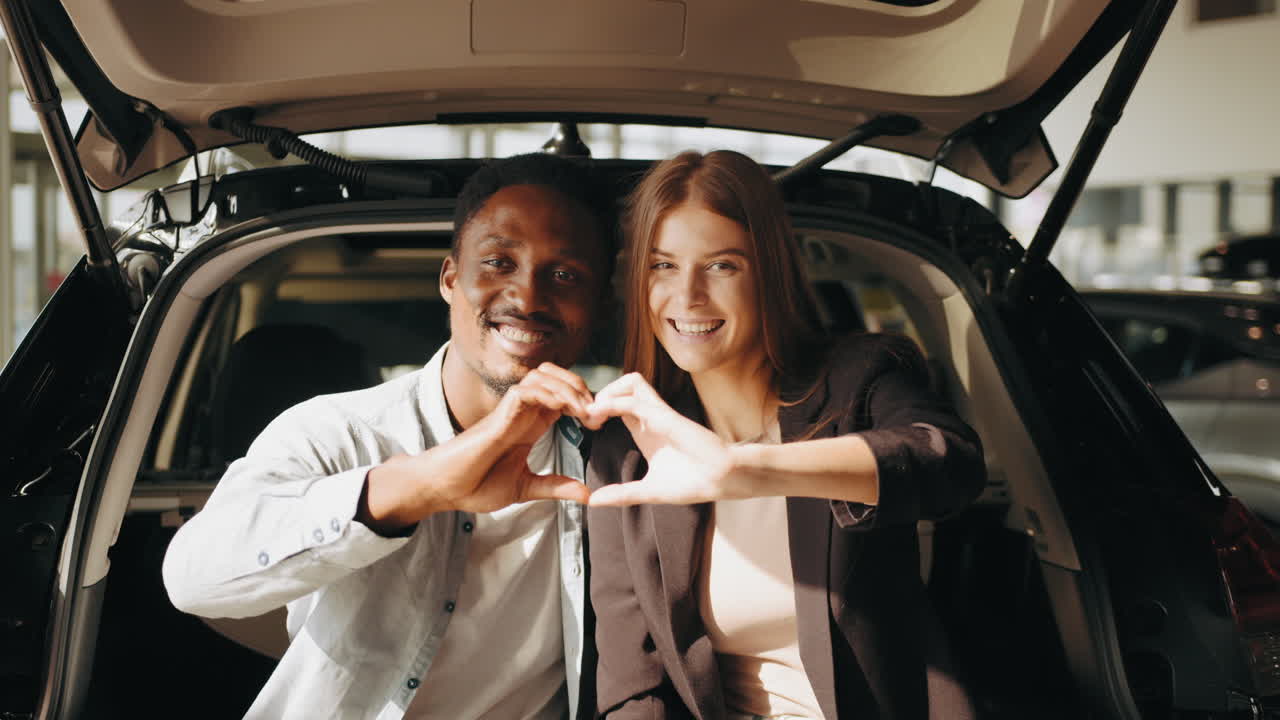una pareja feliz sentada en el maletero del coche.
