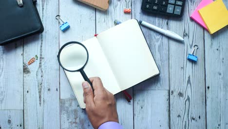 person examining a notebook with magnifying glass