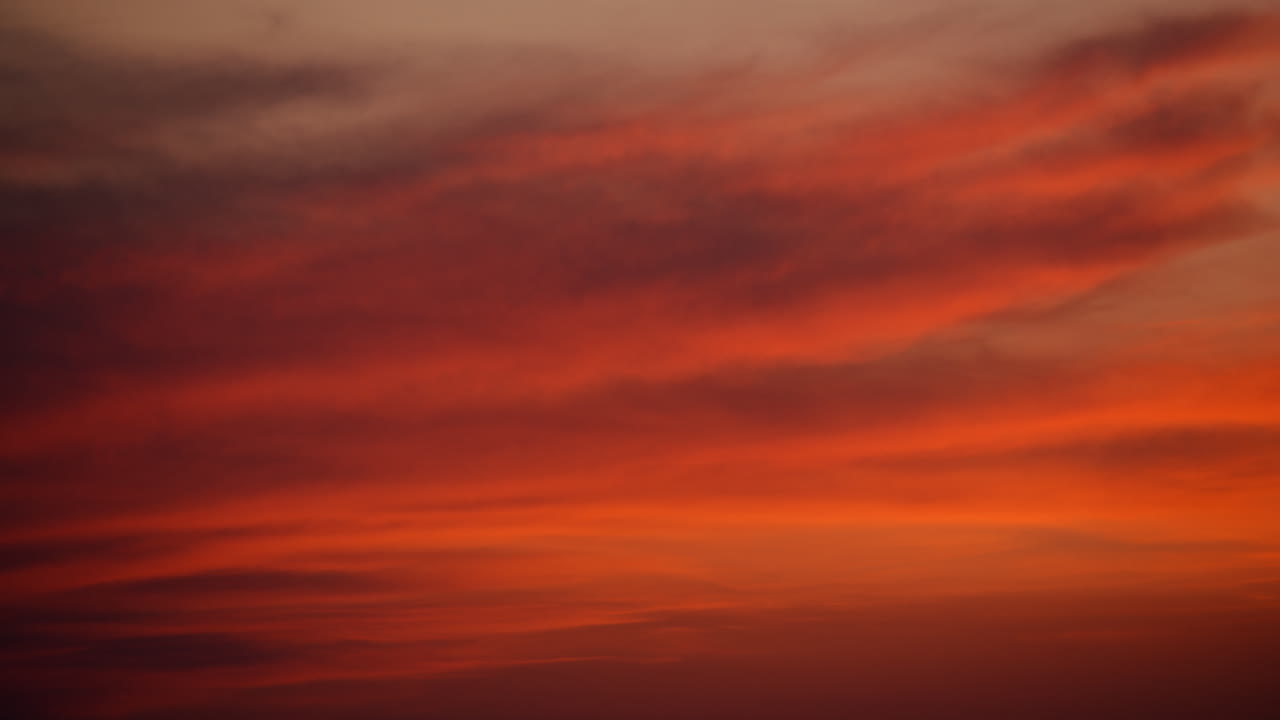 Sunset clouds creating a gradient of fiery red, orange, and golden hues across the sky