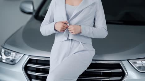 close-up of the face of a slender woman near the car dressed in an elegant light suit