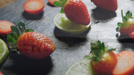 strawberries and lime slices arranged artistically on dark textured surface