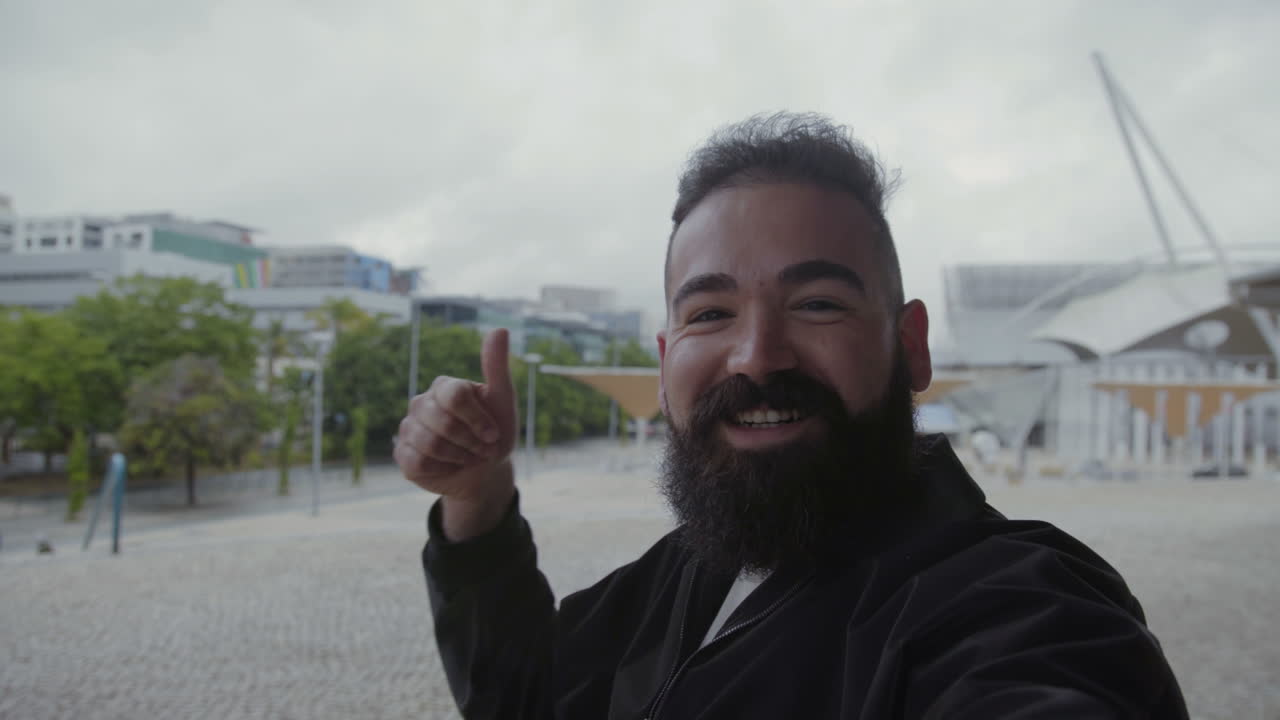미소 짓는 수염을 가진 남자가 비디오를 녹화하는 동안 몸짓을 한다.
