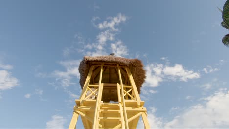 looking up at a bright yellow watch tower on a tropical beach