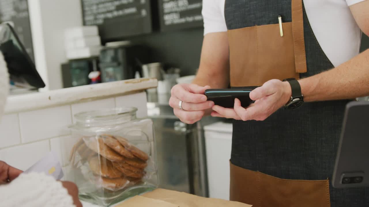 Diverse male barista and female customer paying with credit card in cafe