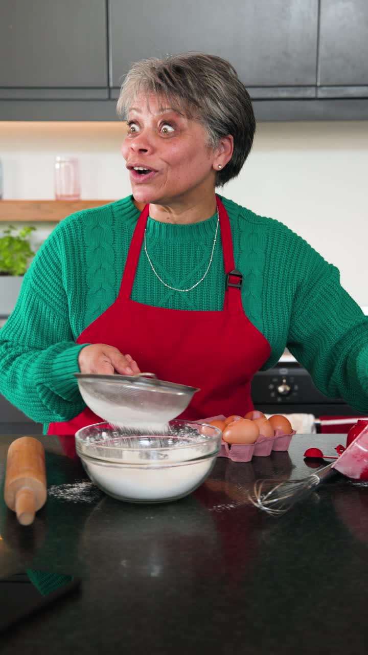 Vertical video: Senior woman baking in kitchen, sifting flour and enjoying holiday preparations