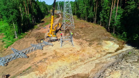 tripulación de grúa erigiendo una torre de transmisión eléctrica - vista aérea