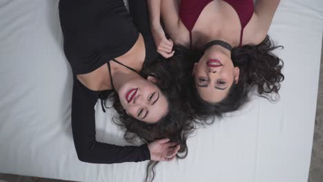two women lying down on a bed