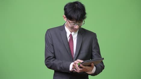 young happy asian businessman smiling while using digital tablet