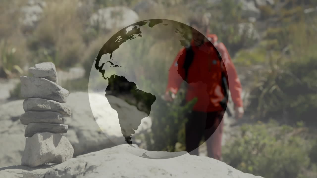 Hiker walking trail past cairn with backpack under digital globe overlay showing technology concept