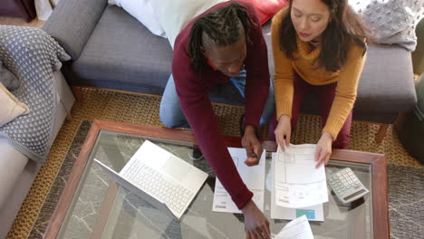 Overhead-of-diverse-couple-with-laptop-discussing-domestic-finance-at-home,-copy-space,-slow-motion