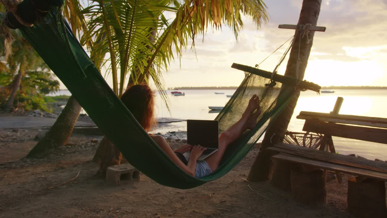Man working with laptop relaxing on hammock on the beach. concept of digital nomad, remote worker, independent location entrepreneur