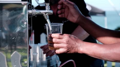 man pours plastic pints of beer at a festival party event