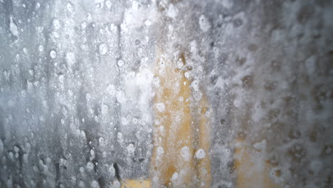 close-up of window being cleaned at car wash, seen from inside car