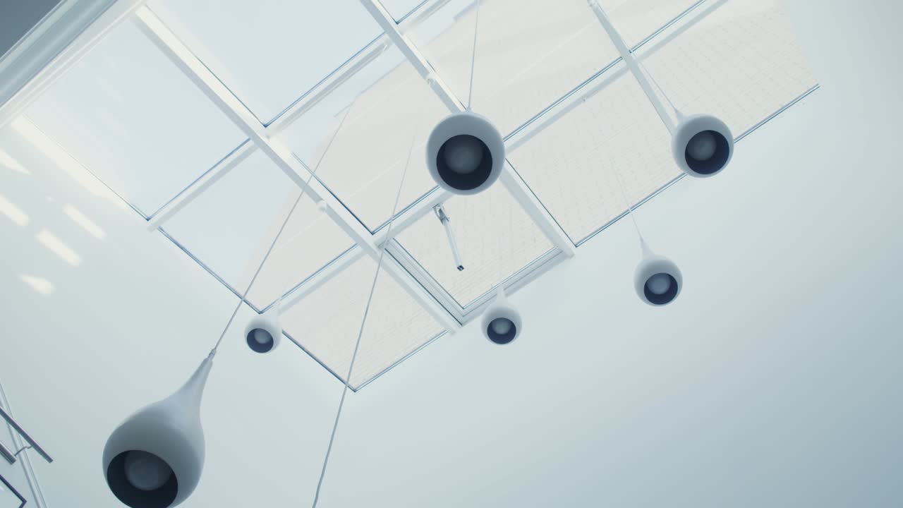 Numerosi lampadari bianchi pendono dal soffitto di vetro