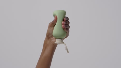 cerca de una mujer apretando una botella de producto de belleza hasta que el contenido salga disparado sobre fondo blanco 2