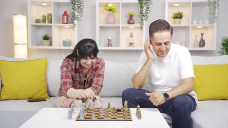 the woman beats her husband in a game of chess. happy couple.