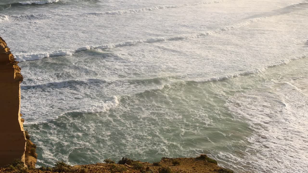 Dynamic ocean waves meet rugged cliff, showcasing nature's power and beauty in a coastal scene.