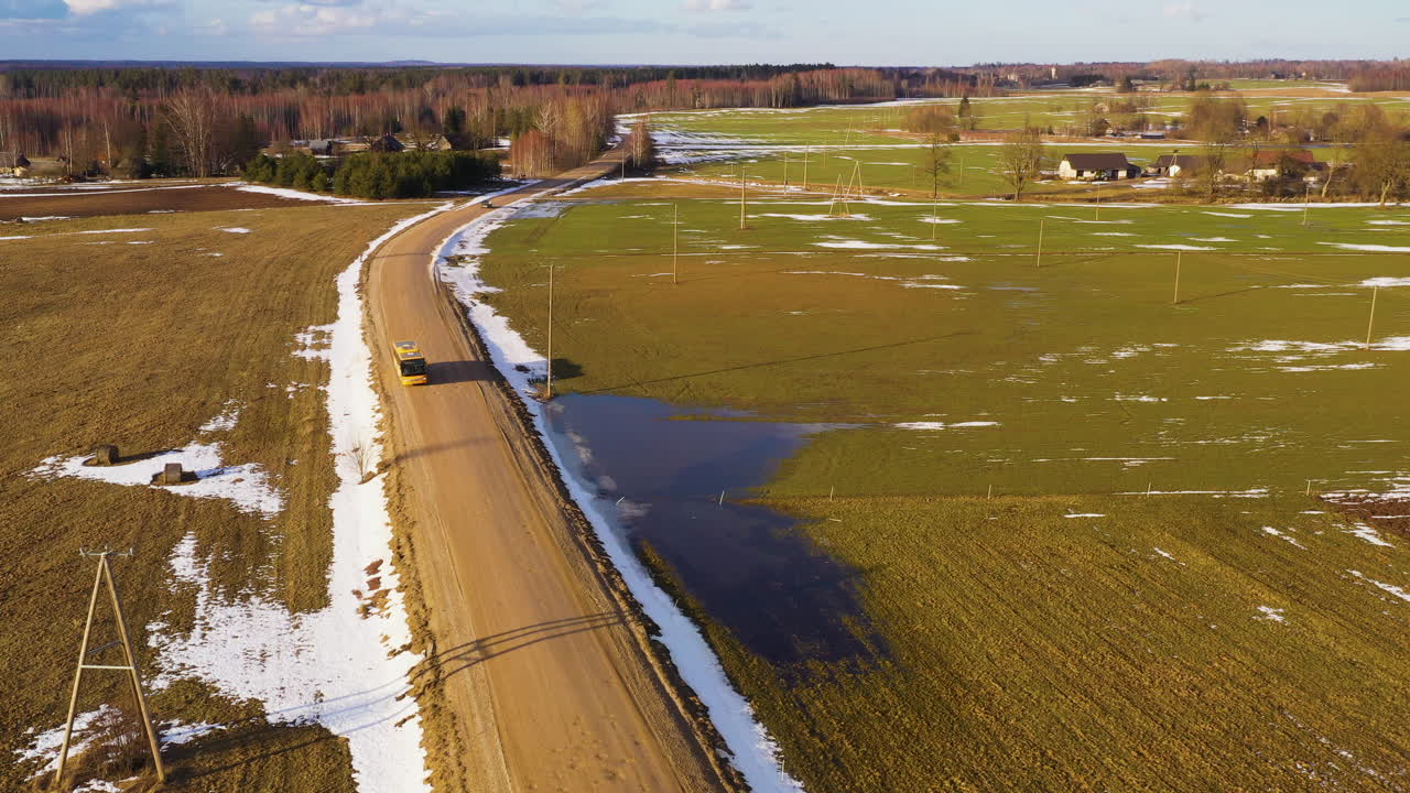 автобус едет по сельской гравийной дороге в начале весны, взгляд с воздуха