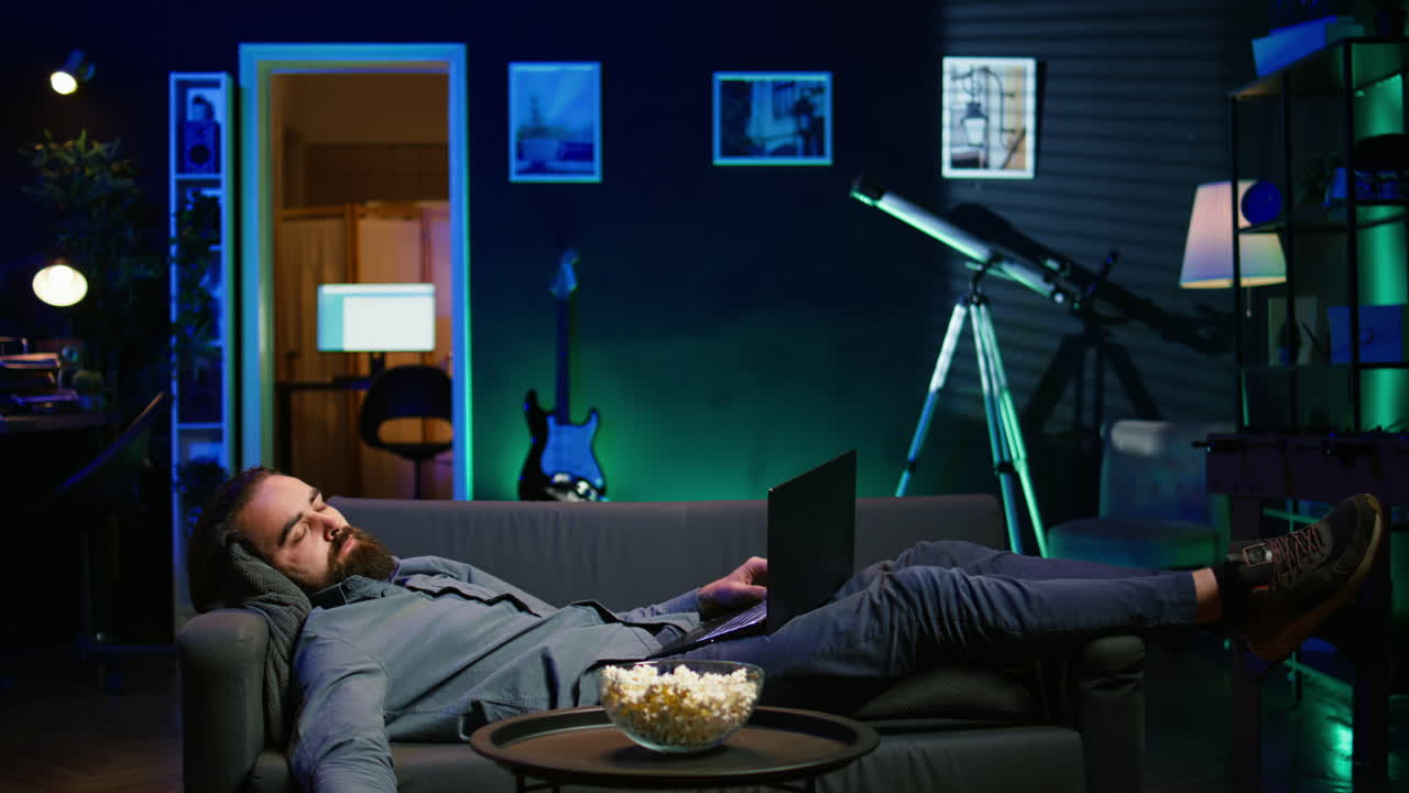 노트북 에서 일 하고 tv 를 보는 후 소파 에서 자고 있는 지친 사람