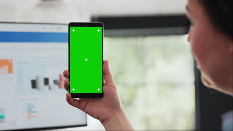 woman holds smartphone at desk