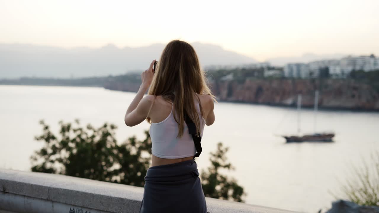 Woman take a photo of city, nature panorama in the dusk