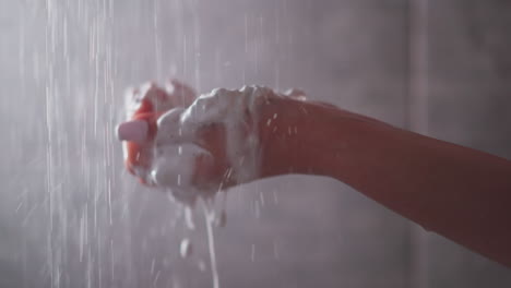 woman washes away foam from palm in shower water closeup. lady uses skin moisturizing mouse for hygienical procedures in bathroom. cosmetic product