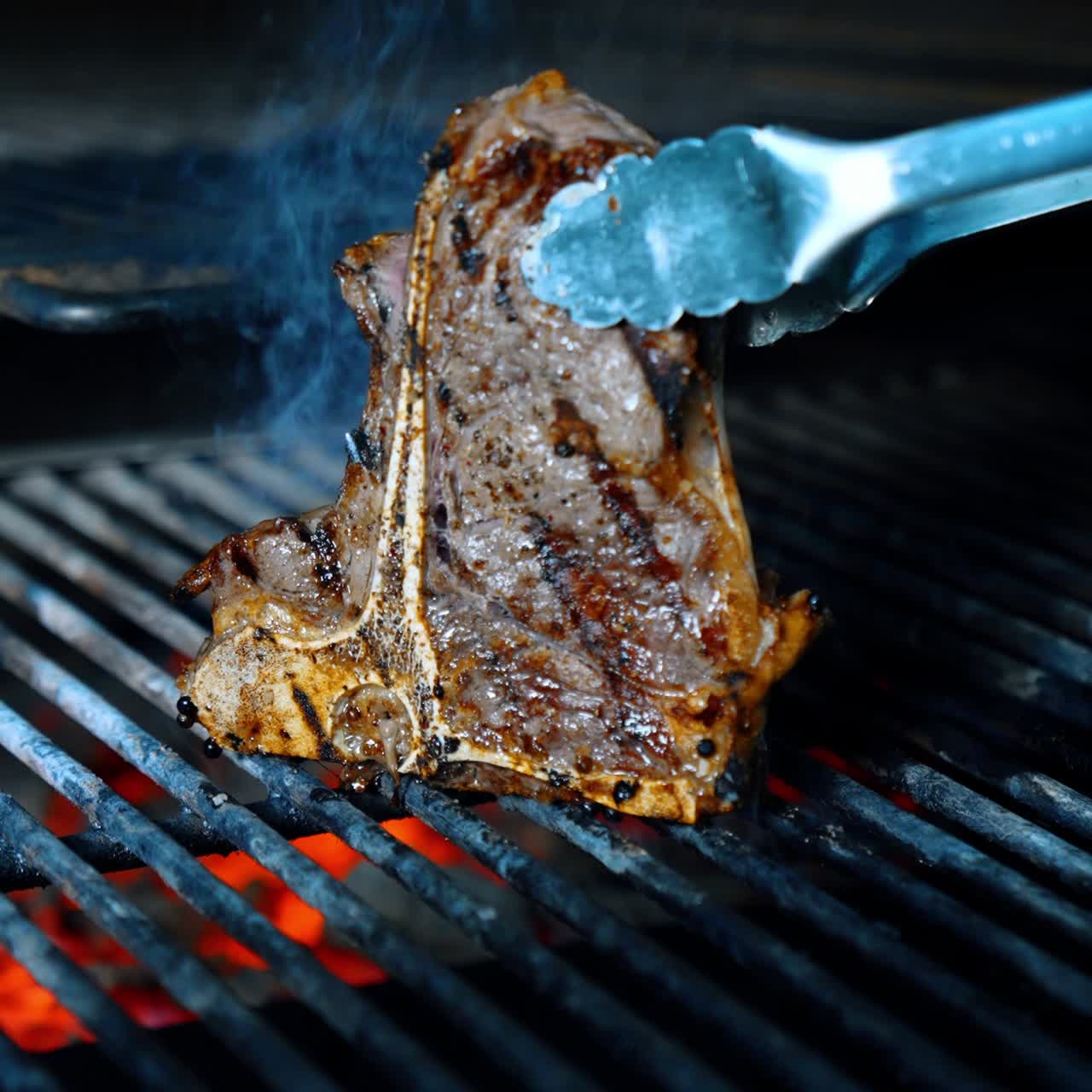 Unrecognized cook turns a piece of meat on the grill with the help of tongs. Close up. Vertical view