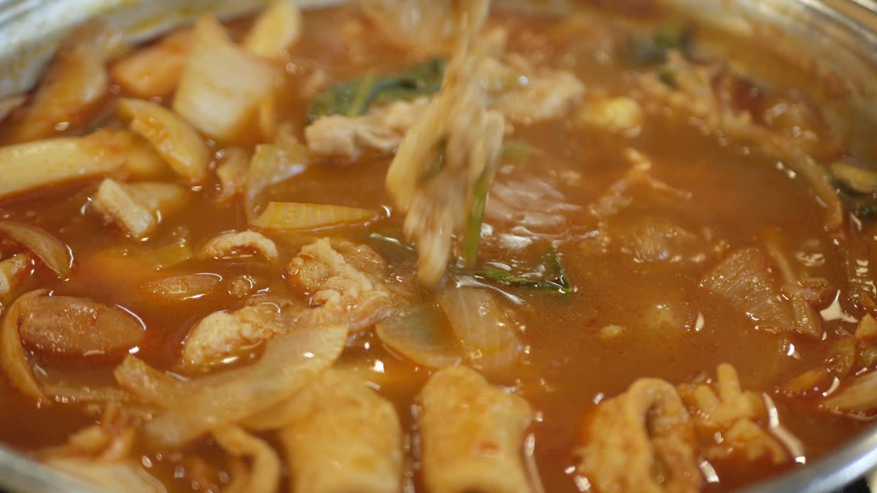 오징어, 홍합, 생선 두부, 생선 국수를 곁들인 한국 김치 수프에서 젓가락 선택 돼지 고기 조각을 사용하는 동안 닫습니다