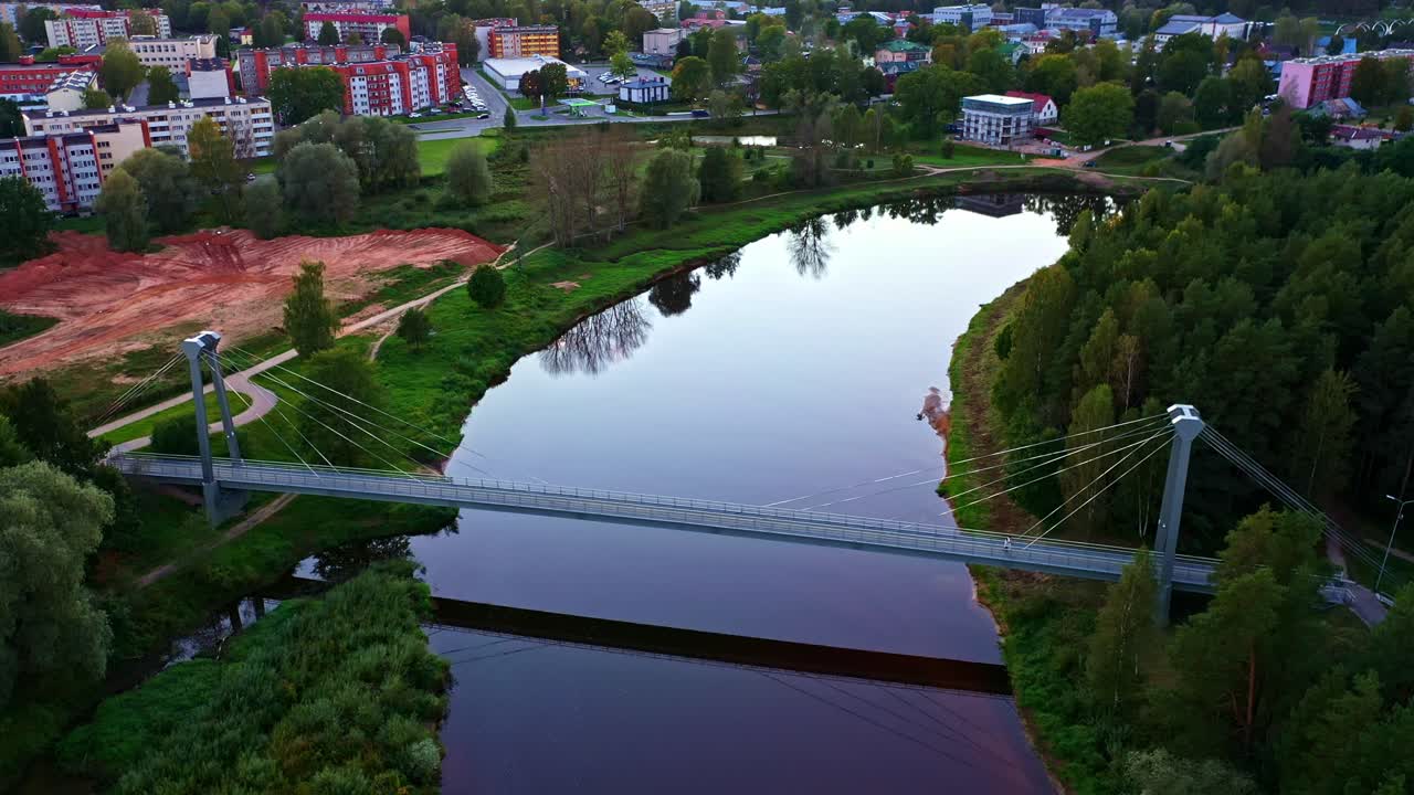Hængebro over Gauja-floden med by og ryddet land i Valmiera, Letland