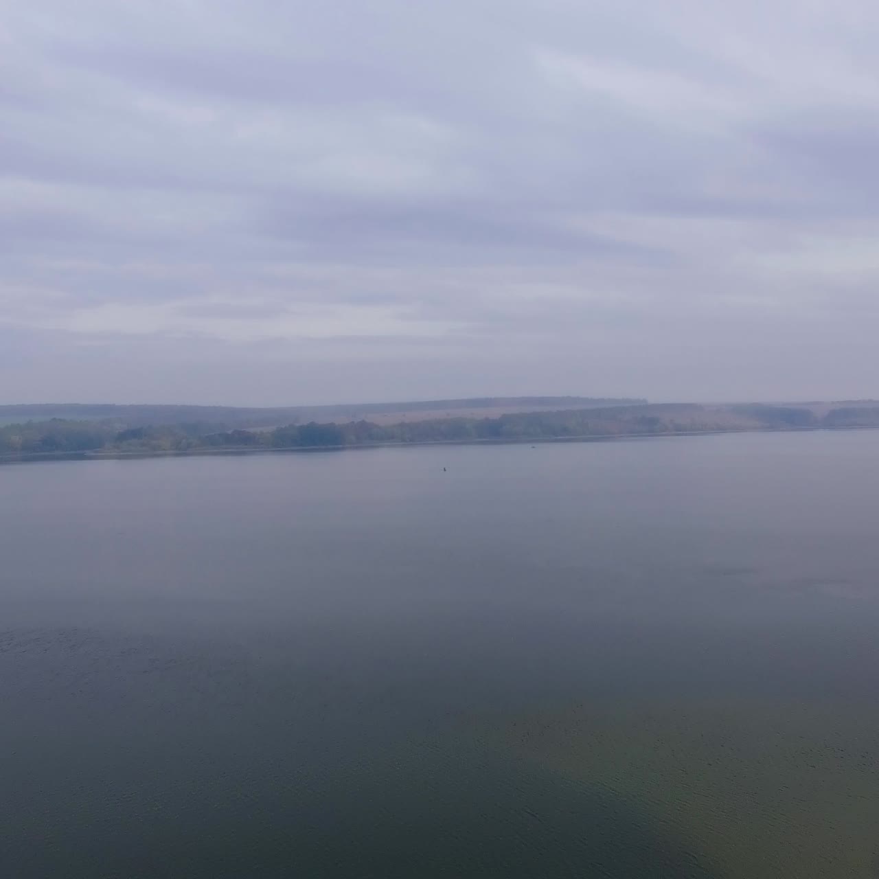 Beautiful white cottages standing on the bank of the river. Few boats are at the shore. Drone footage over the river with foggy waterfront