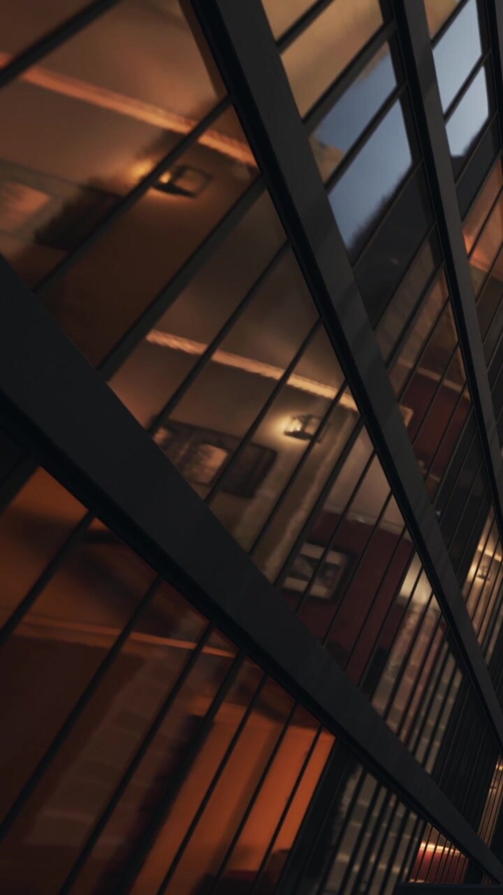 Reflexos de um edifício em vidro durante a noite em uma área urbana.