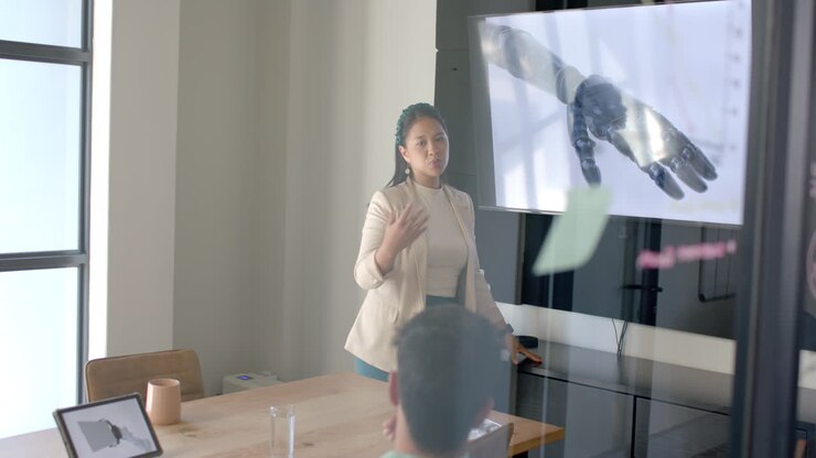 Presenting robotic arm technology, woman giving presentation to colleagues in office