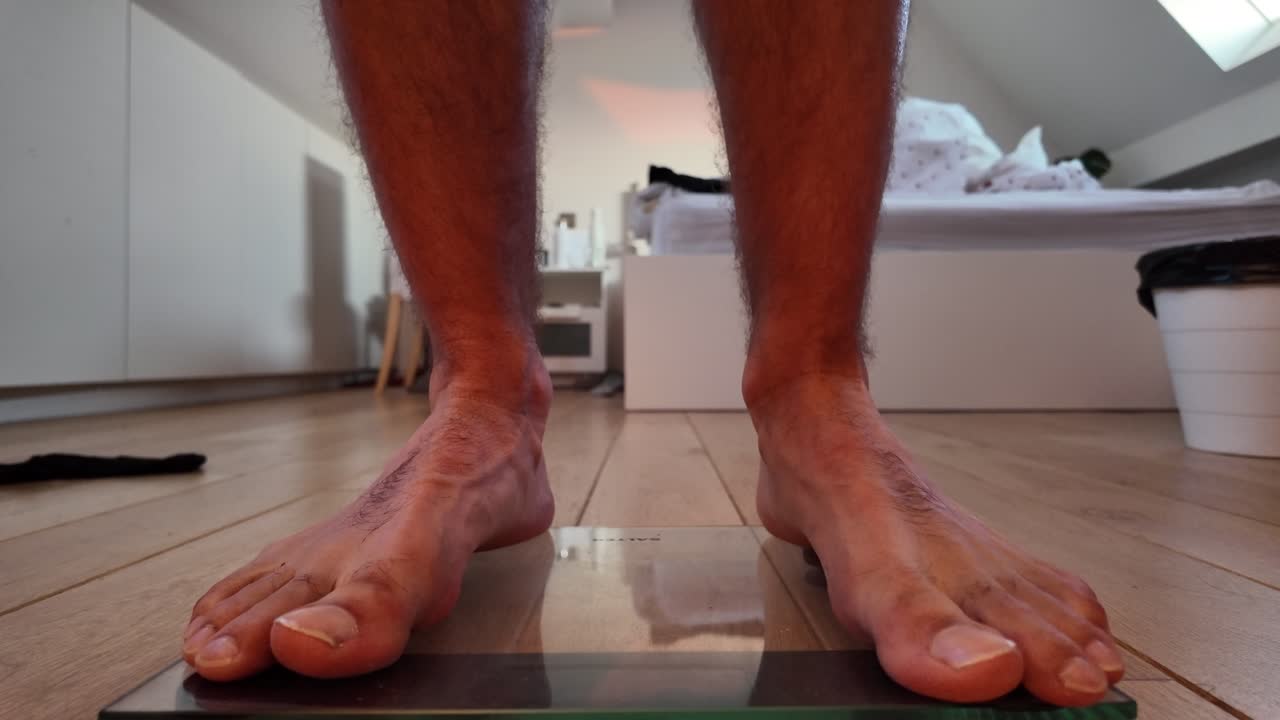 Bare feet firmly standing on glass digital scale at home