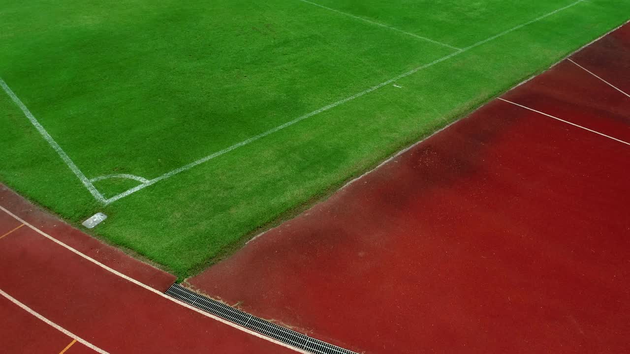 Löparbana och hörna på fotbollsstadion, färgen är tegelröd, högvinkelvy med drönare.