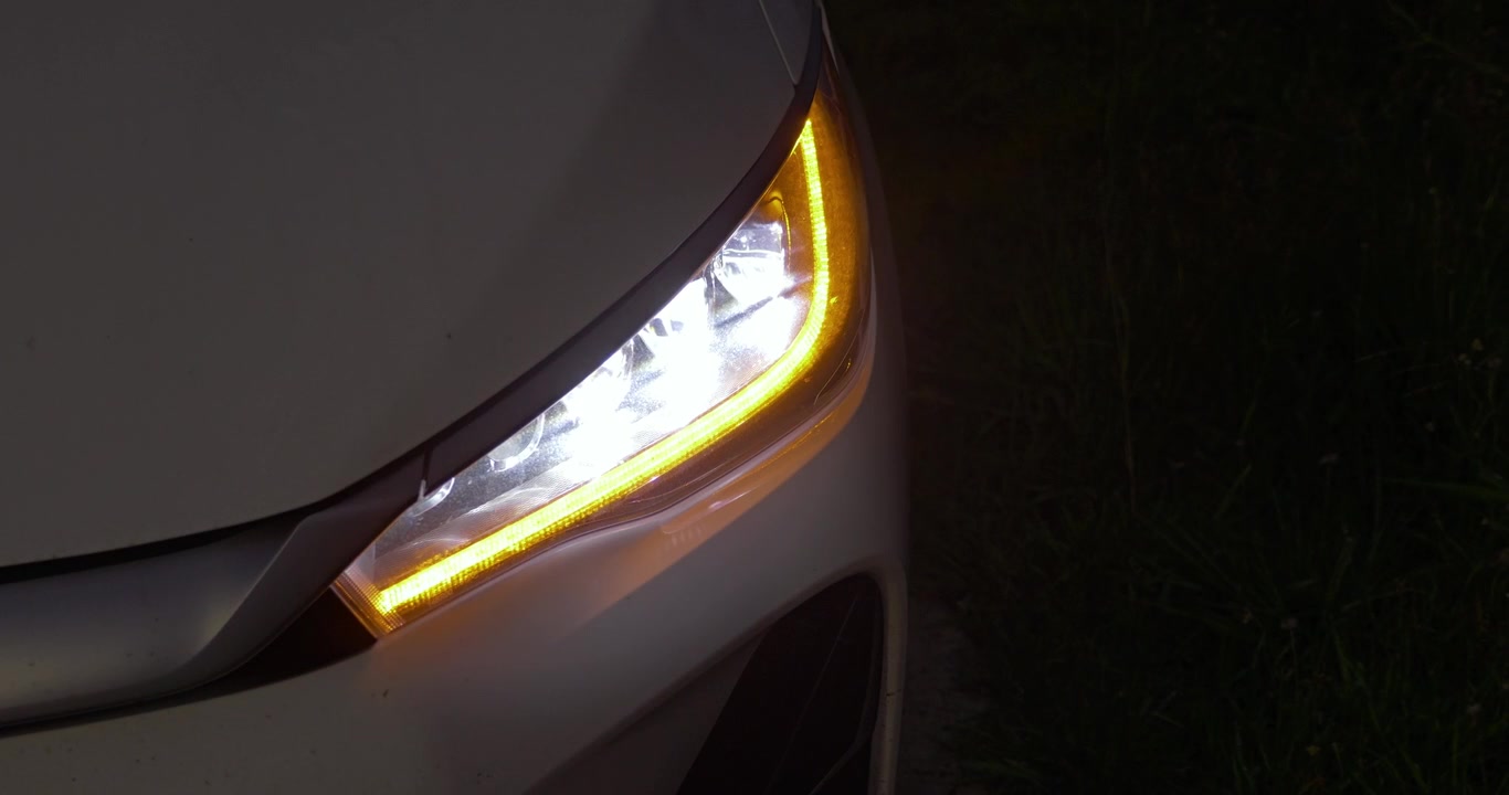 Detailed view of EV car headlights showcasing led design and turn signal in a nighttime environment.