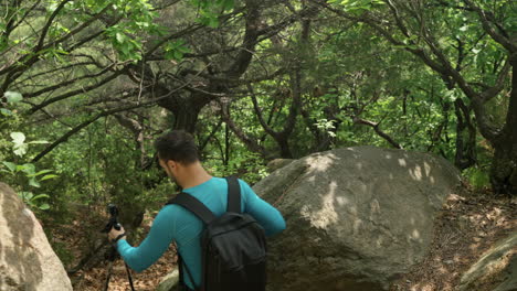 excursionista saltando de una roca enorme en el camino hacia abajo en el sendero del bosque de la montaña