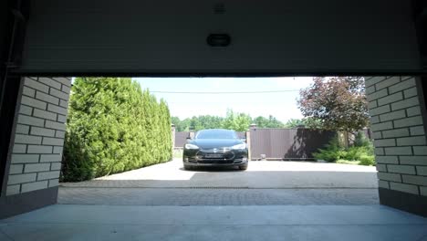 man driver in car thumbed remote control to open the garage door in the house