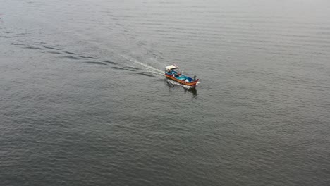 fisherman dropped fishing net into the sea, traditional fishing boat sailing on the sea  out for a morning catch at lumut, mnajung, malaysia, southeast asia, fishery industry shot.